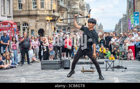 Edimburgo, Regno Unito. 7 agosto 2025. 7 agosto 2025 Edimburgo, Edinburgh Fringe Festival. L'Edinburgh Fringe è ora in pieno svolgimento e la folla si affolla al Royal Mile per sperimentare la varietà di talenti, immagini e suoni degli artisti di strada. Xiao Hei esegue la sua azione di fuoco davanti alla folla PIC Credit: phil wilkinson/Alamy Live News Foto Stock