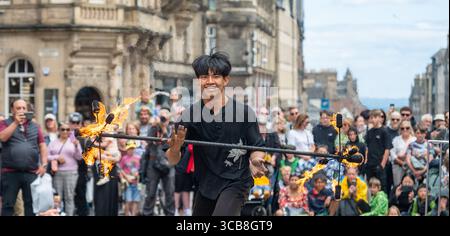 Edimburgo, Regno Unito. 7 agosto 2025. 7 agosto 2025 Edimburgo, Edinburgh Fringe Festival. L'Edinburgh Fringe è ora in pieno svolgimento e la folla si affolla al Royal Mile per sperimentare la varietà di talenti, immagini e suoni degli artisti di strada. Xiao Hei esegue la sua azione di fuoco davanti alla folla PIC Credit: phil wilkinson/Alamy Live News Foto Stock