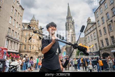 Edimburgo, Regno Unito. 7 agosto 2025. 7 agosto 2025 Edimburgo, Edinburgh Fringe Festival. L'Edinburgh Fringe è ora in pieno svolgimento e la folla si affolla al Royal Mile per sperimentare la varietà di talenti, immagini e suoni degli artisti di strada. Xiao Hei esegue la sua azione di fuoco davanti alla folla PIC Credit: phil wilkinson/Alamy Live News Foto Stock