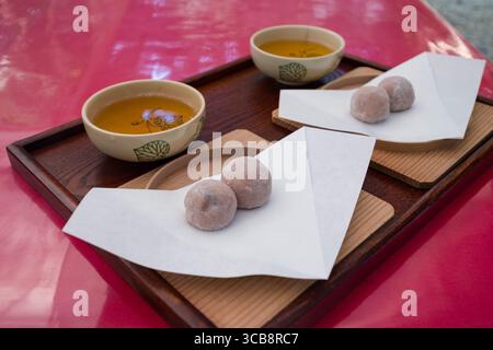 Una deliziosa disposizione di tè matcha e dolci di riso mochi giapponesi serviti su un vassoio di legno, mostrando cucina tradizionale giapponese Foto Stock