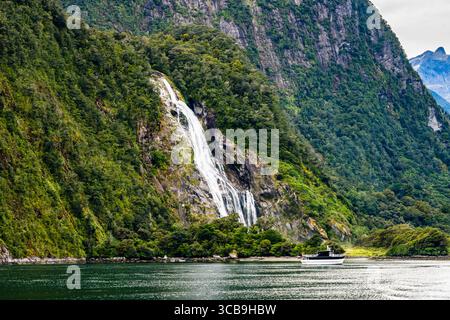 Barca di fronte alle cascate Lady Bowen a Milford Sound, Fiordland National Park, Southland, South Island, nuova Zelanda Foto Stock
