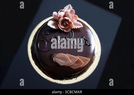 Torta intera di Sachertorte (torta sacher al cioccolato) su sfondo nero. Dessert tradizionale austriaco. Direttamente sopra. Foto Stock