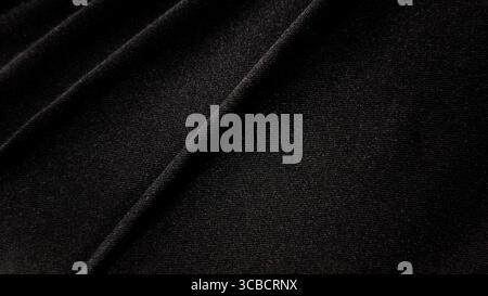 Foto macro di texture scura del tessuto, che mostra l'intricato motivo intrecciato del materiale nero con sfumature e ombre sottili. Dettaglio e enfatizza Foto Stock