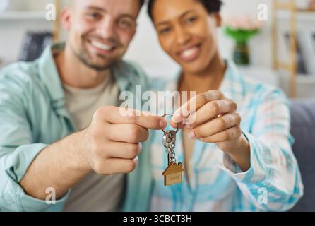 Felice giovane coppia che tiene in mano una chiave seduta in un nuovo appartamento il giorno del trasloco. Foto Stock