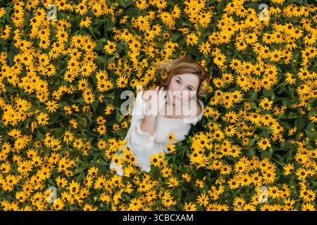 Direttamente sopra la foto di una donna che giace in fiori gialli Foto Stock