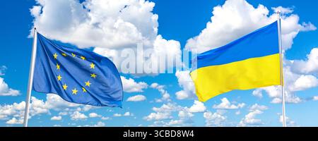 Sventolare le bandiere dell'Ucraina e dell'Unione europea contro il cielo blu con le nuvole Foto Stock