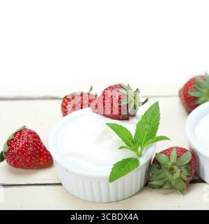 Yogurt greco biologico e fragola su tavola di legno rustico bianco Foto Stock