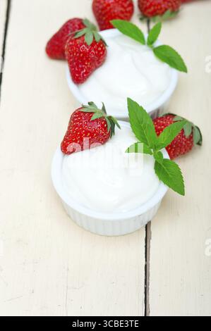 Yogurt greco biologico e fragola su tavola di legno rustico bianco Foto Stock