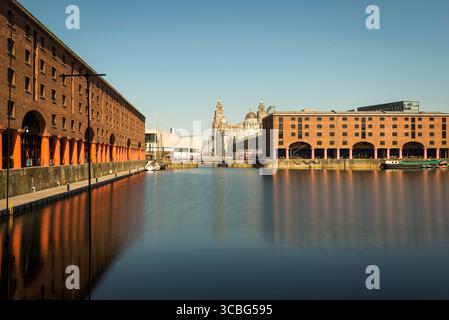 I magazzini Albert Dock con riflessi sull'acqua, si affacciano sulle iconiche tre Grazie di Liverpool. Foto Stock