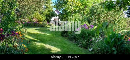 Splendido giardino con prato verde fresco, alberi e fiori con molto spazio. Foto Stock