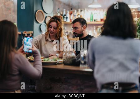 Gruppi di amici che si godono la preparazione del cibo in un accogliente lounge bar Foto Stock