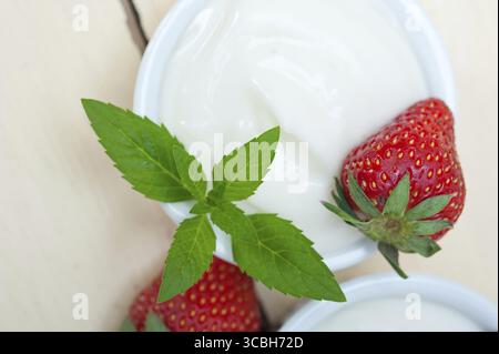 Yogurt greco biologico e fragola su tavola di legno rustico bianco Foto Stock