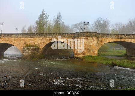 Storico ponte romanico che attraversa il fiume Pisuerga ad Aguilar de Campoo, Palencia, Spagna. Foto Stock