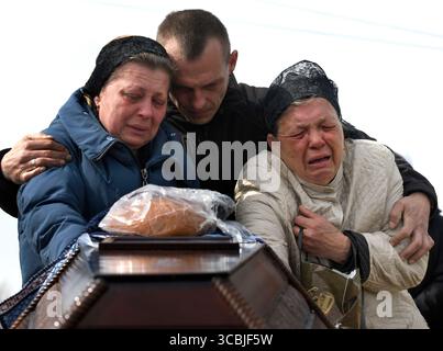 23 aprile 2022, Bucha, Ucraina: 23 aprile 2022, Bucha, Ucraina: Bogdan Volodymerovuch Tromssa, 24 anni, è pianto dalla madre IRYNA TROMSSA, 55 anni, e dalla nonna RAISA OLEKSANDRIVNA RODINA, 73 anni, con lo zio ANDRII al suo funerale a Bucha, Ucraina, il 23 aprile 2022. Era un paracadutista con la 95a brigata uccisa combattendo le forze russe nell'Ucraina orientale. E' morto da qualche parte tra Symu e Kharkiv. Il suo corpo era quasi irriconoscibile. (Immagine di credito: © Carol Guzy/ZUMA Press Wire) Foto Stock