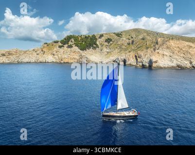 Vista aerea con droni della barca a vela con vela blu sul mare blu Foto Stock