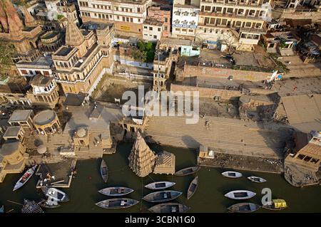 Vista aerea dei ghati che scendono fino al bordo del fiume, dove le barche si ondeggiano dolcemente, incorniciate dall'antica architettura, Varanasi, Uttar Pradesh, India. Foto Stock