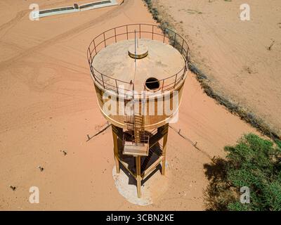 Veduta aerea di una torre d'acqua sbiadita che si erge in alto contro il paesaggio arido, il suo metallo che riflette la dura luce del sole, Khol Khol, regione di Louga, Senegal Foto Stock