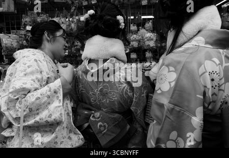 Durante l'inverno, le donne in kimono colorati si possono sfogliare in articoli di carattere in un negozio nella via dello shopping di Nakamise Foto Stock