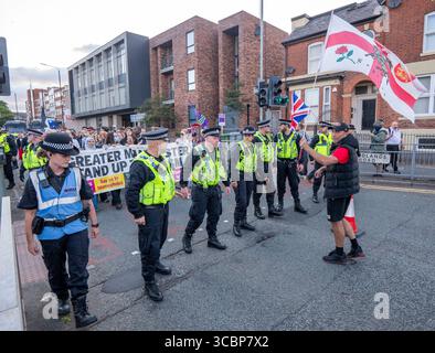 Manchester, Regno Unito. 8 agosto 2025. La polizia scorta i manifestanti "resistono al razzismo" mentre sono affiancati da manifestanti di destra. Protesta e contro protesta al Cresta Court Hotel, Altrincham, Manchester Regno Unito. I manifestanti anti anti-migranti discutono con la polizia. I manifestanti preoccupati per l'uso dell'hotel per ospitare i richiedenti asilo riuniti nel tardo pomeriggio. I manifestanti includevano il gruppo delle donne i “manifestanti rosa”. Una contro protesta di “Stand Up to Racism” si è riunita anche in hotel. La polizia separò i due gruppi e una barriera temporanea era in atto nella riserva centrale. Altrincham, Manchester. C Foto Stock