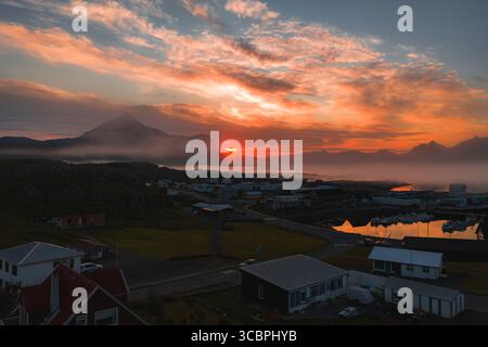 Tramonto sulla città costiera islandese con montagna sullo sfondo Foto Stock