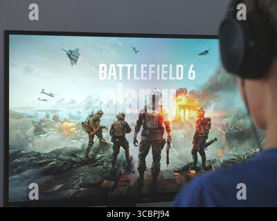 Tambov, Federazione Russa - 8 agosto 2025 Un giovane seduto dietro un computer con la schermata di caricamento del gioco Battlefield 6. Foto Stock
