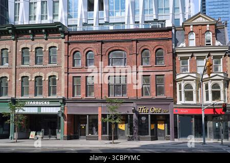 Toronto, Canada - 8 agosto 2025: Edifici commerciali storici del XIX secolo integrati con un alto e moderno edificio in Yonge Street Foto Stock