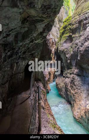 Stretta passerella scavata sulla scogliera lungo un torrente turchese all'interno della gola di Partnachklamm, Garmisch-Partenkirchen, Baviera. Uno splendido pass naturale Foto Stock