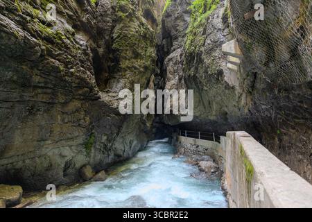 Stretta passerella scavata sulla scogliera lungo un torrente turchese all'interno della gola di Partnachklamm, Garmisch-Partenkirchen, Baviera. Uno splendido pass naturale Foto Stock