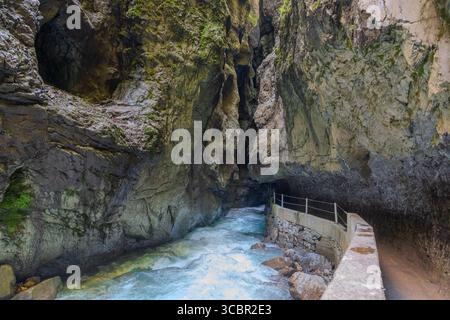 Stretta passerella scavata sulla scogliera lungo un torrente turchese all'interno della gola di Partnachklamm, Garmisch-Partenkirchen, Baviera. Uno splendido pass naturale Foto Stock