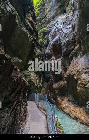 Stretta passerella scavata sulla scogliera lungo un torrente turchese all'interno della gola di Partnachklamm, Garmisch-Partenkirchen, Baviera. Uno splendido pass naturale Foto Stock