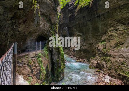 Stretta passerella scavata sulla scogliera lungo un torrente turchese all'interno della gola di Partnachklamm, Garmisch-Partenkirchen, Baviera. Uno splendido pass naturale Foto Stock