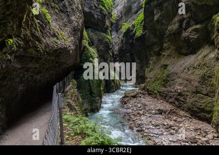 Stretta passerella scavata sulla scogliera lungo un torrente turchese all'interno della gola di Partnachklamm, Garmisch-Partenkirchen, Baviera. Uno splendido pass naturale Foto Stock