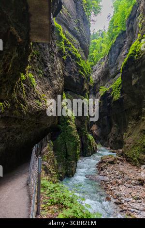 Stretta passerella scavata sulla scogliera lungo un torrente turchese all'interno della gola di Partnachklamm, Garmisch-Partenkirchen, Baviera. Uno splendido pass naturale Foto Stock