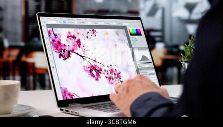 Giovane stilista maschio che modifica le foto sul suo computer portatile Foto Stock