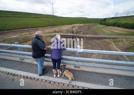 Yorkshire, Gran Bretagna. 8 agosto 2025. La gente guarda al lago Baitings quasi esausto nello Yorkshire, in Gran Bretagna, l'8 agosto 2025. I livelli dei bacini idrici hanno recentemente continuato a diminuire man mano che l'aumento del consumo di acqua ha incontrato la mancanza di pioggia in Gran Bretagna. Crediti: Jon Super/Xinhua/Alamy Live News Foto Stock