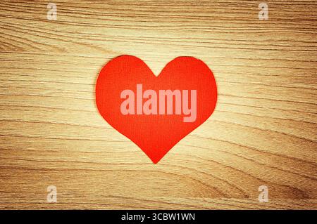 Foto di vignettatura della forma del cuore rosso sul primo piano dello sfondo del pannello di legno Foto Stock
