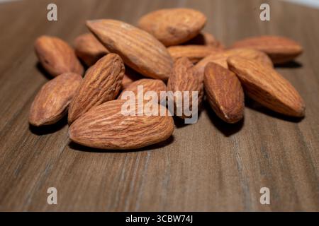 Mandorle marrone su sfondo di legno Foto Stock