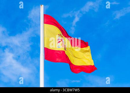 Bandiera nazionale della Spagna che sventola nel vento; bandiera nazionale rossa e gialla su sfondo blu del cielo Foto Stock