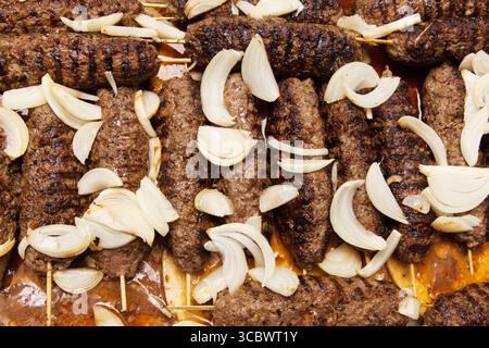 Carne alla griglia su spiedini di legno cosparsi di cipolle da vicino. Lula - kebab. Foto Stock