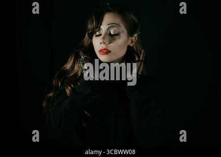 Ritratto di una giovane donna in un'immagine gotica cupa di una strega o di un vampiro. Costume di Halloween. Foto Stock