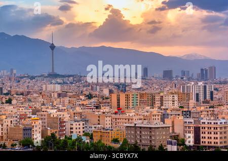 Splendido panorama cittadino al tramonto della città di Teheran, delle montagne e della torre Milad durante il colorato tramonto in Iran. Foto Stock