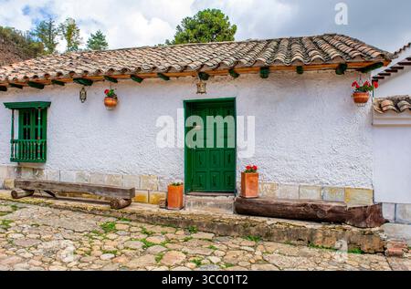 Affascinante architettura coloniale con una porta verde e una finestra a Monguí, Boyacá. Le strade acciottolate ne esaltano il fascino pittoresco. Foto Stock