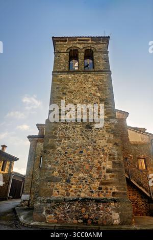 Campanile in pietra della chiesa di San Pedro a Pino del Rio, Palencia, sotto un cielo azzurro. Foto Stock