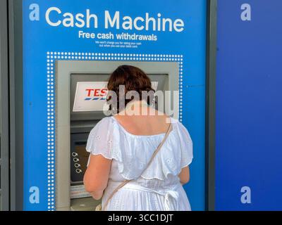 Pontypridd, Galles, Regno Unito - 12 luglio 2025: Persona che ritira denaro da un bancomat al di fuori della filiale di Tesco Express nel centro di Pontypridd Foto Stock