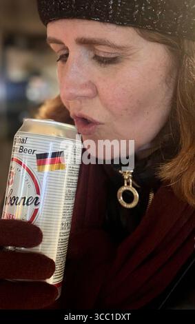 Donna vestita per sorseggiare l'inverno da una lattina all'aperto in un ambiente freddo. Foto Stock