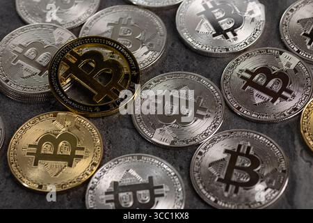 Una disposizione di monete Bitcoin d'oro e d'argento poste su una superficie di pietra testurizzata, simboleggiando concetti di criptovaluta e valuta digitale. Foto Stock