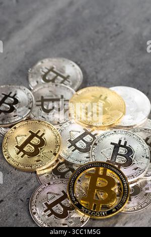 Una disposizione di monete Bitcoin d'oro e d'argento poste su una superficie di pietra testurizzata, simboleggiando concetti di criptovaluta e valuta digitale. Foto Stock