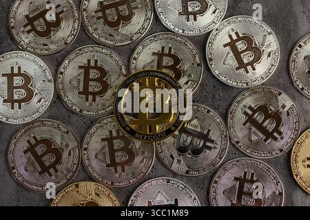 Una disposizione di monete Bitcoin d'oro e d'argento poste su una superficie di pietra testurizzata, simboleggiando concetti di criptovaluta e valuta digitale. Foto Stock