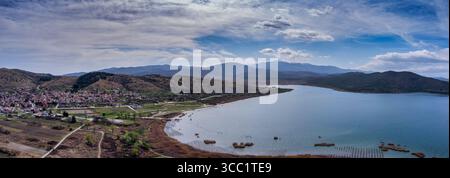 Vista aerea di Arnissa, Grecia, con il lago Vegoritida accanto alla città. Circondato da colline e montagne, questo tranquillo paesaggio fonde natura e tra Foto Stock