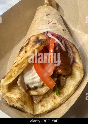Tradizionale gyro di maiale greco in pita grigliata con pomodoro, cipolla e salsa tzatziki. Foto Stock